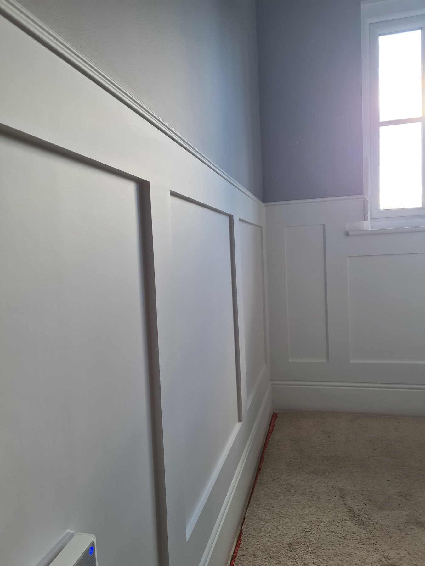 Wall panelling painted white with grey walls above, Abergele