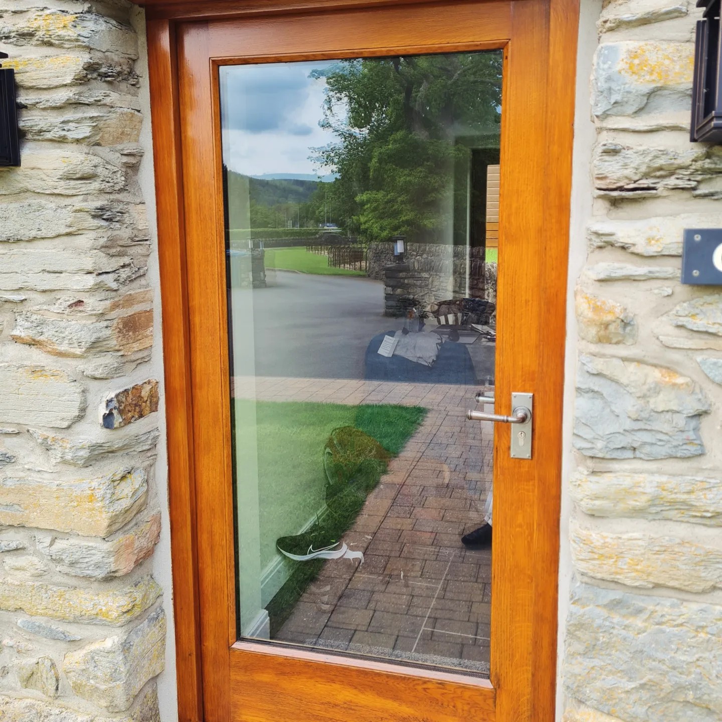 Oak door with Sikkens woodstain in Medium Oak beside stone wall, Betws-y-Coed