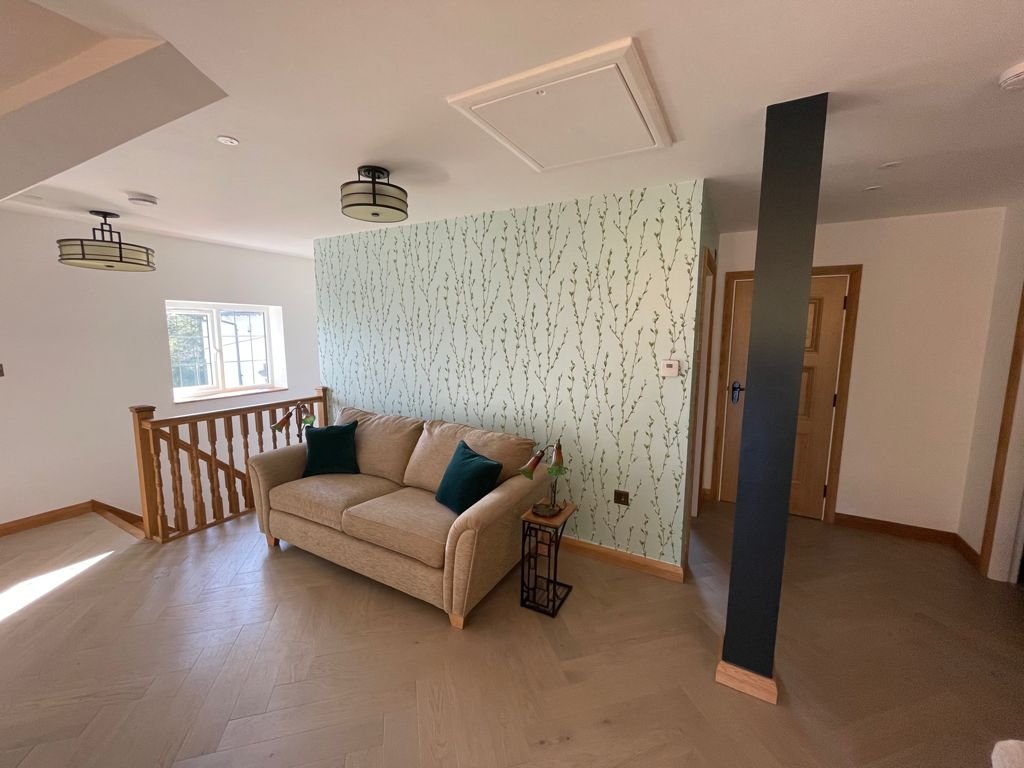 Landing with willow feature wallpaper and sofa beside oak balustrade, annexe in Conwy
