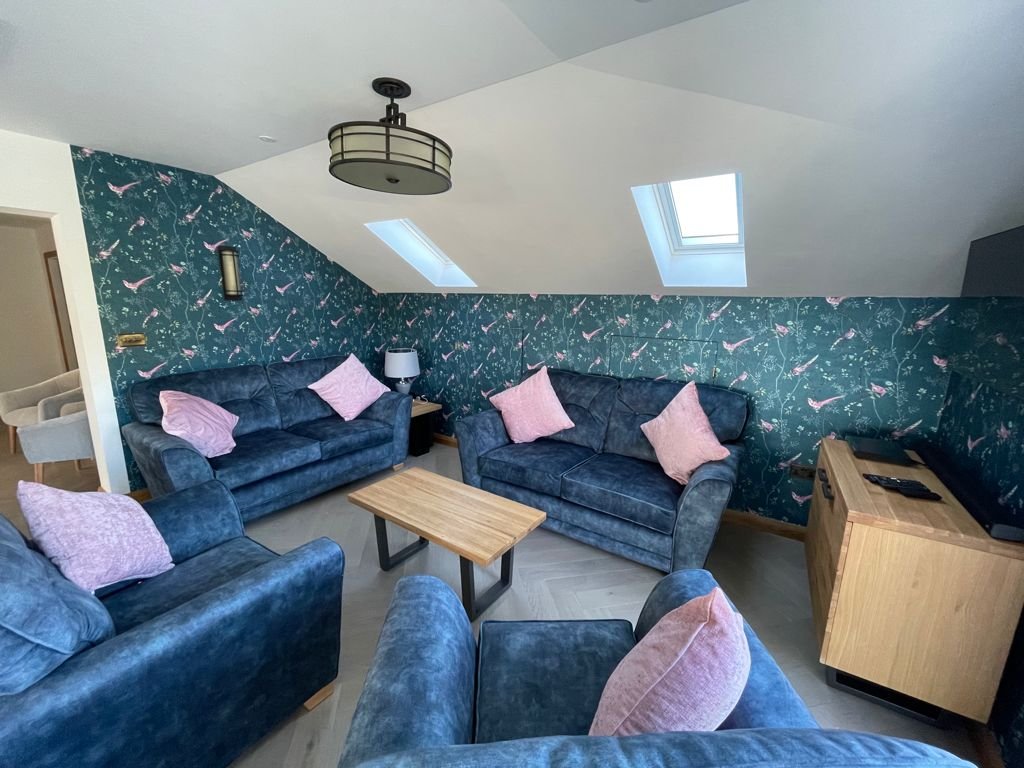 Lounge with teal bird wallpaper and painted sloping ceiling with skylights, Conwy annexe