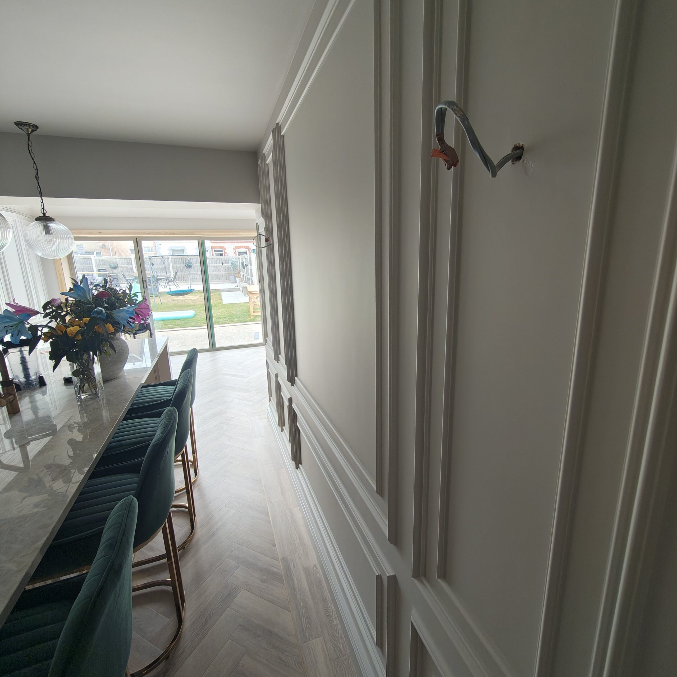 Painted panelled hallway wall leading to the kitchen island and garden doors in Conwy